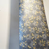 A bold, maximalist and romantic wallpaper, featuring a botanical, Japanese and Arts and Crafts-inspired design in metallics, blues, pink and yellow, with a subtle pearlescence or shimmer. A length of Wild Lone's "Berry Galaxy" wallpaper in "Smoky Grey".