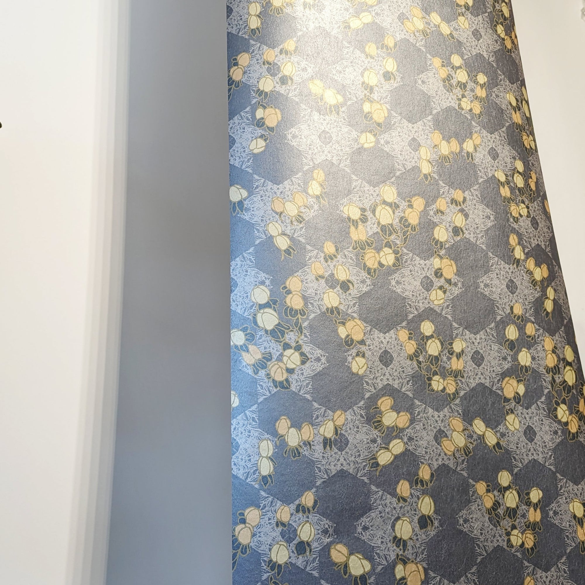 A bold, maximalist and romantic wallpaper, featuring a botanical, Japanese and Arts and Crafts-inspired design in metallics, blues, pink and yellow, with a subtle pearlescence or shimmer. A length of Wild Lone's "Berry Galaxy" wallpaper in "Smoky Grey".
