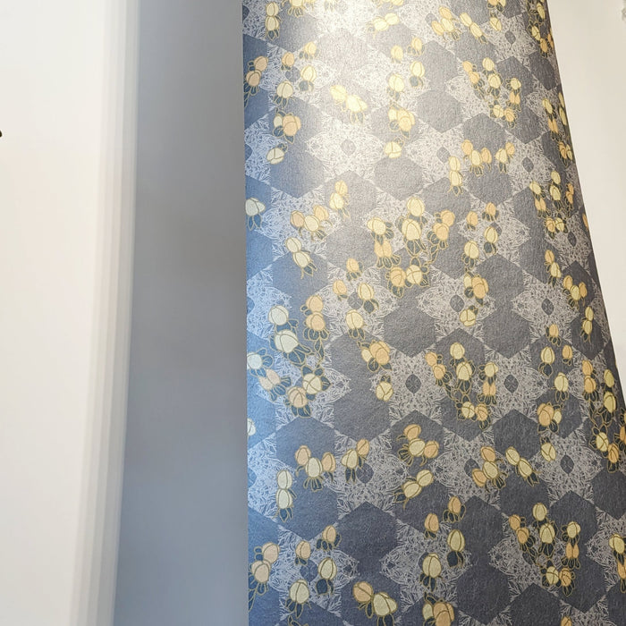 A bold, maximalist and romantic wallpaper, featuring a botanical, Japanese and Arts and Crafts-inspired design in metallics, blues, pink and yellow, with a subtle pearlescence or shimmer. A length of Wild Lone's "Berry Galaxy" wallpaper in "Smoky Grey".