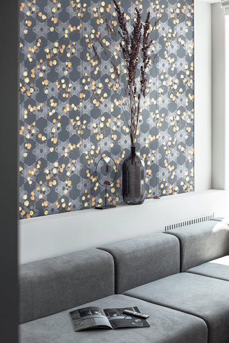 A luxurious, maximalist wallpaper featuring a botanical, Japanese and Arts and Crafts-style pattern in metallics, blue, grey, pink and yellow, with a subtle shimmer, in a modern living room with a grey sofa. Wild Lone's "Berry Galaxy" wallpaper in "Smoky Grey".