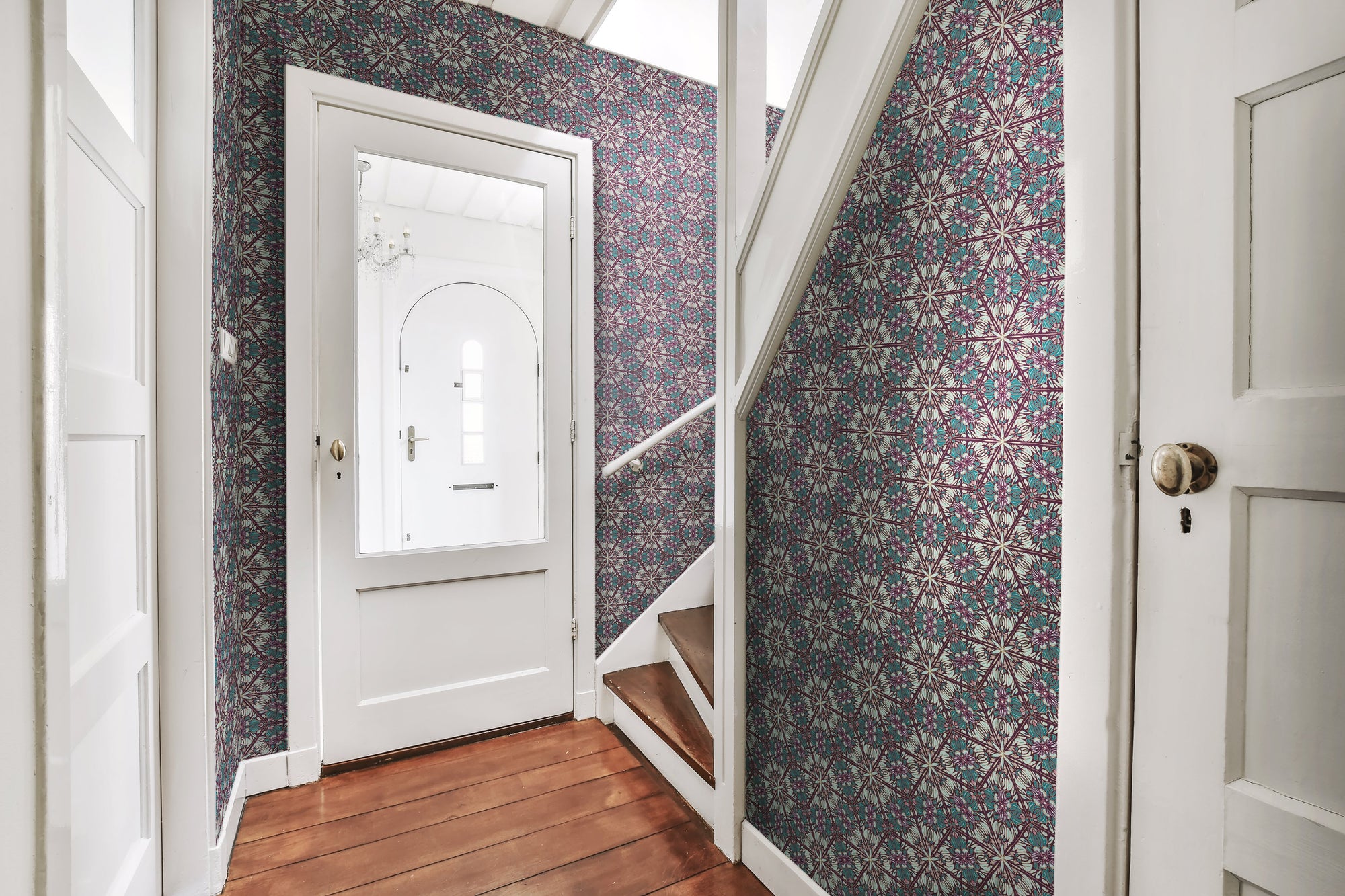 A bold, intricate and moody wallpaper featuring a botanical, Art Nouveau and Japanese-inspired pattern in purple, pink, greens and gold, in an entranceway and staircase in a period apartment. Wild Lone's "Greenhouse" wallpaper in "Exotic Green".