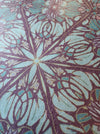 A closeup of Wild Lone's "Greenhouse" wallpaper in "Exotic Green", showing the subtle pearlescence or shimmer, and fibrous texture, and intricate botanical design, inspired by Art Nouveau and Japanese pattern, with purple, pink, greens and gold. 