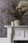 An elegant Georgian fireplace and decor in a period living room, with an intricate green, purple, pink and gold wallpaper. Wild Lone's "Greenhouse" wallpaper in "Exotic Green" features a botanical pattern, inspired by Art Nouveau and Japanese design, with a gentle pearlescence or shimmer.