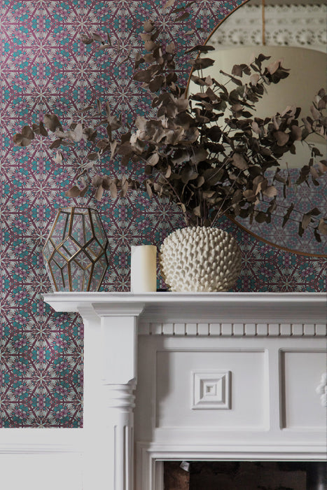 An elegant Georgian fireplace and decor in a period living room, with an intricate green, purple, pink and gold wallpaper. Wild Lone's "Greenhouse" wallpaper in "Exotic Green" features a botanical pattern, inspired by Art Nouveau and Japanese design, with a gentle pearlescence or shimmer.