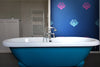 A bold, statement wallpaper on a feature wall in a bathroom with a traditional bathtub, featuring metallic blue and magenta bee forms against a dark blue background, with a gentle shimmer or pearlescence. Wild Lone's "Night Flight" wallpaper in "Electric Blue".