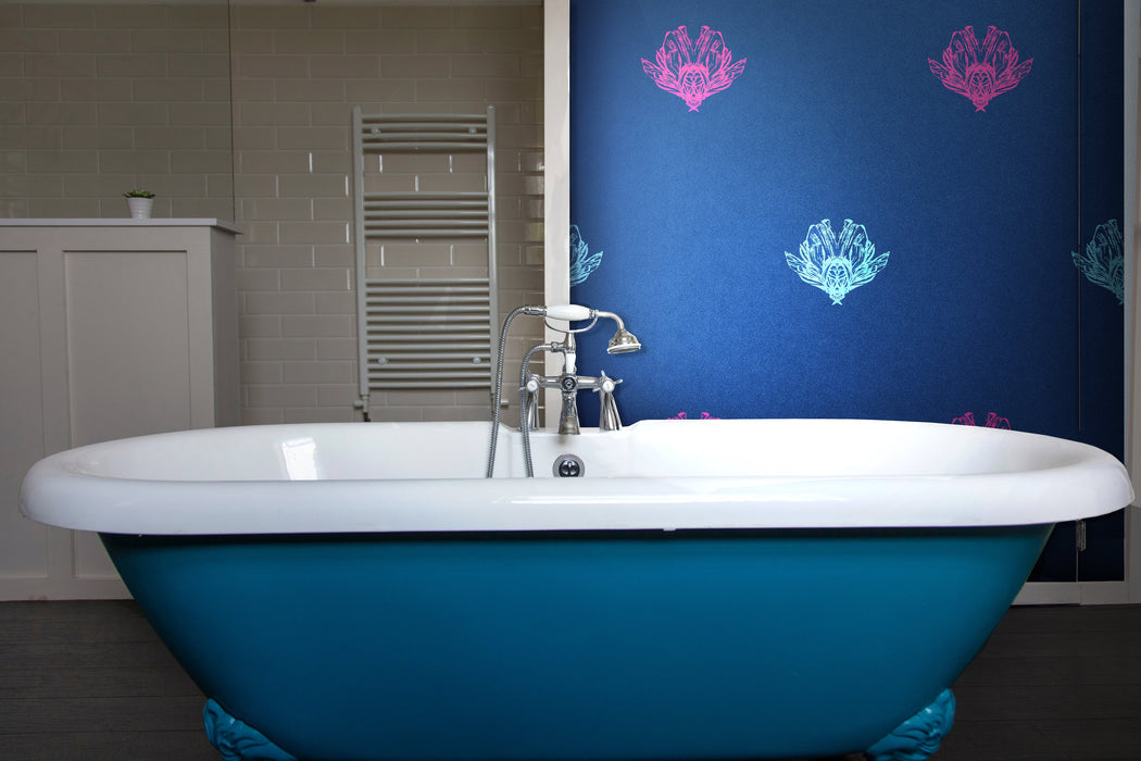 A bold, statement wallpaper on a feature wall in a bathroom with a traditional bathtub, featuring metallic blue and magenta bee forms against a dark blue background, with a gentle shimmer or pearlescence. Wild Lone's "Night Flight" wallpaper in "Electric Blue".