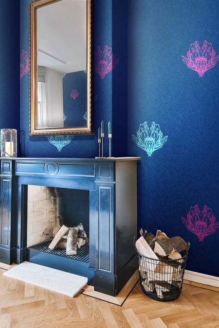 A deep blue, bold wallpaper with a mood of dark romance, featuring electric blue and magenta bee forms, with a subtle pearlescence or shimmer, on a feature wall in a period living room, surrounding a fireplace. Wild Lone's "Night Flight" wallpaper in "Electric Blue".
