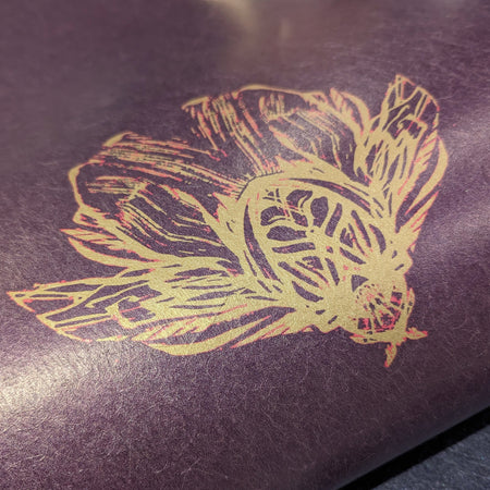 Closeup detail of the fantastical bee in Wild Lone's "Night Flight" wallpaper, in the "Purple Jewel" colourway. A luxurious, pearlescent wallpaper with a mood of dark romance, featuring antique gold, magenta and jewel purple.
